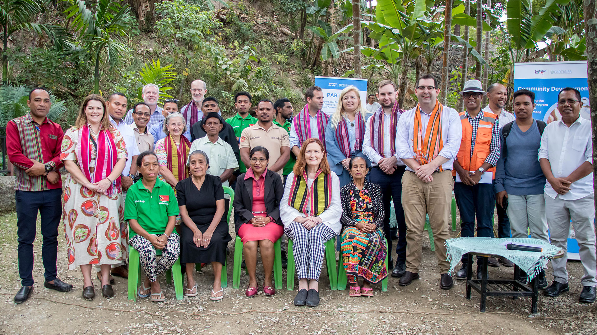 A group of Australian people are seated and standing with Timorese staff and village members during a visit to some PARTISIPA work sites in Dare.